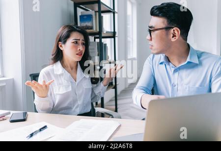 Zwei asiatische Kollegen streiten sich hitzig miteinander Stockfoto