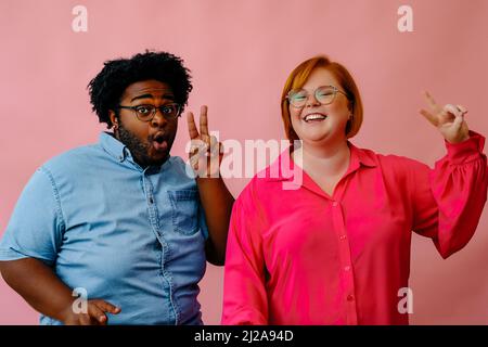 Glückliche Freunde posieren zusammen im Studio über rosa Hintergrund Freundschaft Millennial Stockfoto