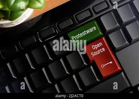 Protestware und Open Source-Taste auf einer pc-Tastatur. Protestware ist, wenn ein Programmierer bösartige Inhalte in einen Open-Source-Code einfügen, um zu machen Stockfoto