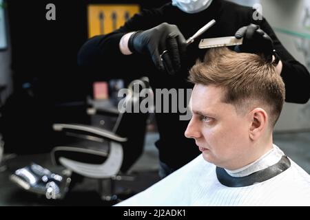 Besuch im Friseurladen. Stilvoller Mann macht modische Frisur. Friseur, Friseur, Stylistin mit Schere, Kammschnitt, dryer.Combing Haare. Kunde, Kunde Stockfoto