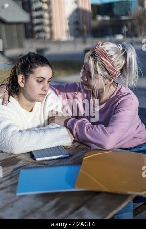 Junge Frau Teenager umarmen, um ihre traurigen besten Freunde von dem Gefühl nach unten von Trennung mit Freund im Freien zu beruhigen. Stockfoto