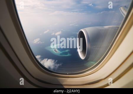 Blick vom Flugzeugfenster während der Landung auf den Malediven. Indischer Ozean mit wunderschönen tropischen Inseln an idyllischen sonnigen Tagen. Stockfoto