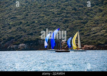 Bodrum, Mugla, Türkei - 02.25.2022: Segelboote mit offenen bunten Segeln. Das Rennteam navigiert durch den Wind auf Wellen auf See. Yachten bei der Regatta. Stockfoto