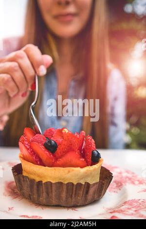 Junge Frau, die Kuchen mit Erdbeertochter verkostet, selektiver Fokus. Stockfoto