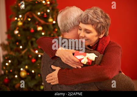 Das Geschenk des Gebens. Eine kurze Aufnahme eines liebevollen Seniorenpaares, das an Weihnachten Geschenke austauscht. Stockfoto