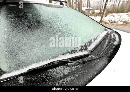 Eisiger Regen erzeugt eine Eisschicht und übersticht ein Personenfahrzeug. Nahaufnahme der Windschutzscheibe Stockfoto
