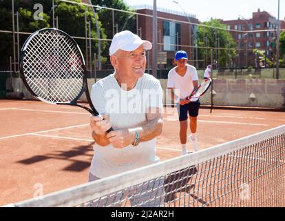 Großvater und Enkel spielen Tennisplatz Stockfoto