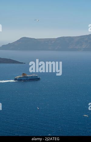 Santorini, Griechenland - 10. Mai 2021 - Eine Fähre verlässt den Hafen von Athinios in Santorini und Möwen fliegen herum Stockfoto