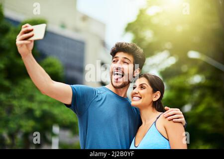 Fitness ist der Grund für ihre fröhliche Stimmung. Aufnahme eines sportlichen jungen Paares, das gemeinsam im Freien ein Selfie gemacht hat. Stockfoto