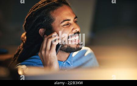 Wir können morgen dann weiter sprechen Ausgeschnittene Aufnahme eines jungen Designers, der sich auf einem Mobiltelefon unterhielt, während er spät in einem Büro arbeitete. Stockfoto