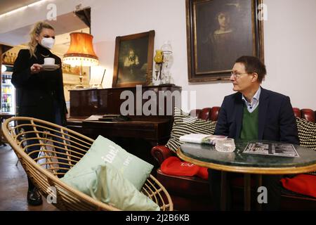 Köln, Deutschland. 31. März 2022. Bundesgesundheitsminister Karl Lauterbach (r, SPD) wird in seinem Stammcafe in Köln einen Kaffee serviert. Quelle: Oliver Berg/dpa/Alamy Live News Stockfoto