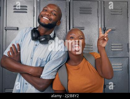 Zwei junge schwarze Studenten posieren mit dummen Gesichtern vor den Schließfächern des Campus Stockfoto
