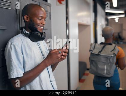 Eine junge trendige schwarze Studentin auf seinem Handy, Frau geht vorbei Stockfoto
