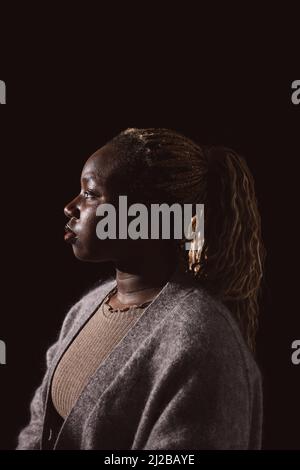 Kontemplative Frau mit schwarzem Hintergrund im Studio Stockfoto