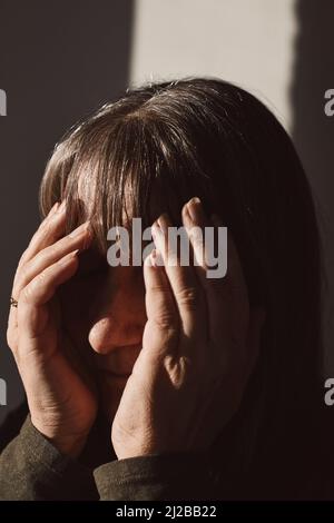 Reife Frau bedeckt Gesicht im Studio Stockfoto