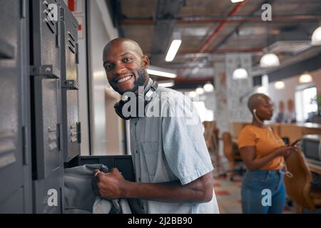 Eine junge schwarze Studentin legt seine Tasche in das Schließfach auf dem Campus, mit einem Hintergrund für eine junge Frau Stockfoto