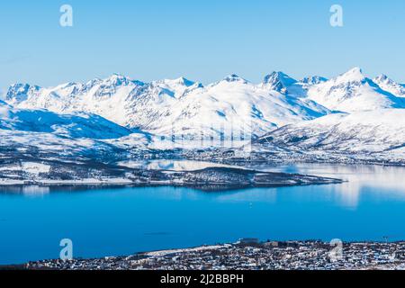 Blick auf die norwegische Stadt Tromso in Norwegen und verschneite Berge und Fjorde dahinter, Kopierraum Stockfoto