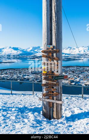 Ein Aussichtspunkt mit Wegweiser in der Fjellheisen-Seilbahn, Berg Storsteinen in Tromso, Norwegen, mit hölzernen Pfeilen, die Touristen zeigen Stockfoto