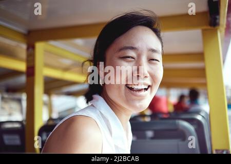 Begleiten Sie mich auf ein Abenteuer. Ein Porträt einer attraktiven jungen Frau, die tagsüber auf einer Fähre die Stadt allein erkundet. Stockfoto