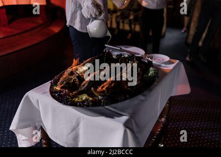Großes Stück gebratenes Fleisch auf Feuer beim Koch im Restaurant Stockfoto