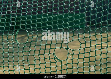 Fußballnetz mit Löchern auf einem Spielplatz Stockfoto