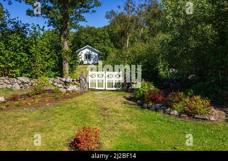 Idyllisches Anwesen mit kleinem Häuschen und Gartentor in der grünen, Süd-Koster-Insel, Bohuslän, Västra Götalands län, Schweden. Stockfoto