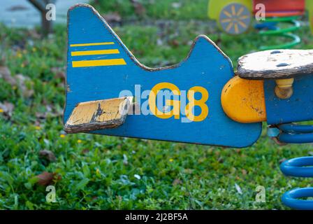 Die Wippe Schaukel in Form eines hölzernen Flugzeugs mit dem Frühling bei den Kindern ist das Spielplatzdetail des Schwanzes Stockfoto