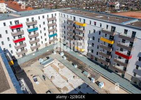 08. März 2022, Sachsen, Leipzig: Nach dem teilweisen Ausbau des Gerüsts sind die Neubauten der Leipziger Wohnungs- und Baugesellschaft (LWB) in der Saalfelder Straße erstmals richtig zu sehen. Die neue Wohnanlage mit 300 Wohnungen besteht aus 18 Häusern, die in sechs Blöcken um zwei Wohnhöfe angeordnet sind. Eine Tiefgarage bietet Platz für 170 Fahrzeuge. Voraussetzung für den Einzug ist eine Bescheinigung über die Wohnberechtigung. Nach zuletzt stagnierenden Zahlen hat sich der Sozialwohnungsbestand in Sachsen etwas erholt. (Luftaufnahme mit Drohne) P Stockfoto