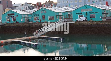 Alte Lagerhäuser, jetzt türkisfarbene Geschäfte und Restaurants, stehen am Wasser im historischen und farbenfrohen Alten Hafen von Reykjavik, Island Stockfoto