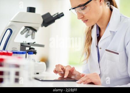 Protokollieren ihrer Ergebnisse online. Eine kleine Aufnahme einer jungen Wissenschaftlerin, die ihre Ergebnisse auf einem digitalen Tablet aufzeichnete. Stockfoto
