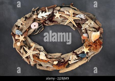 Abstrakter, rustikaler Kranzrahmen aus Treibholz, Muschel und Algen auf meliertem Grau. Seaside Skulptur Kunst Hintergrund, natürliche Komposition. Stockfoto