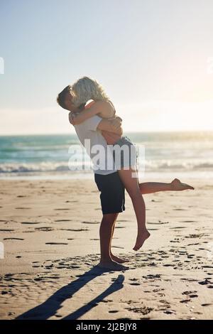 Wir haben diese besondere Art von Liebe. Aufnahme eines liebevollen Paares, das sich einen Kuss teilt, während er Zeit am Strand verbringt. Stockfoto