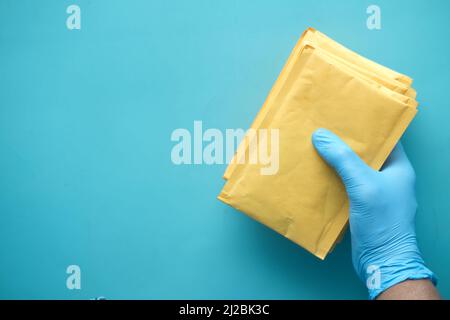 Hand in Latexhandschuhe mit weißem Papier Luftpolsterfolie für Postversand. Stockfoto