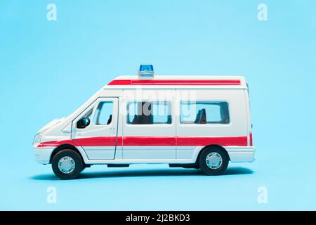 Ein weißer Spielzeugwagen mit roten Linien auf blauem Hintergrund. Spezieller Transport, Spielwarenladen. Stockfoto