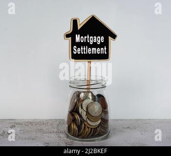 Hypothekenabrechnung Text auf Holzhaus Modell mit Glas voller Münzen auf einem Schreibtisch. Stockfoto