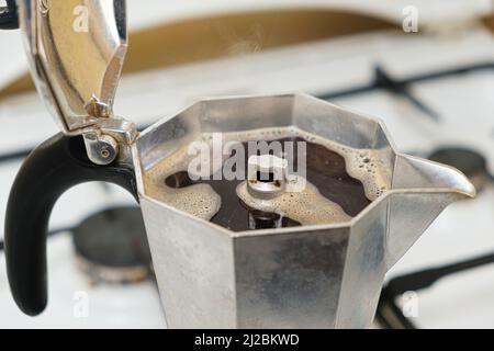 Heißer, frisch gebrühter Kaffee in einer Geysir-Kaffeemaschine, die auf einem Gasherd steht Stockfoto