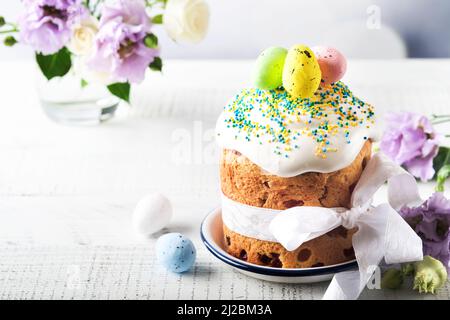 Traditionelles, süßes Osterbrot oder Kuchen mit weißer Puderfarbe und Zuckerdekor und Wachteleiern über dem weißen Holztisch. Verschiedene Ostergebäck im Frühling. Frohes Ea Stockfoto