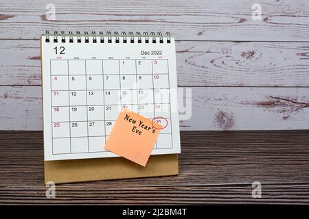 Dezember 2022 Kalender auf Holztisch mit Datumskreis und Text auf Haftnotiz. Silvester am 31.. Dezember 2022. Stockfoto
