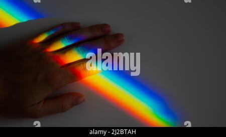 Regenbogenstrahl auf der Hand einer Frau. Stockfoto