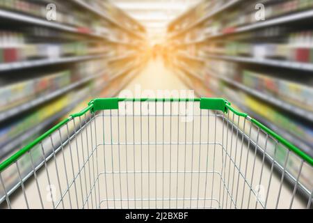 Einkaufswagen mit verwacklungsunscharfem Hintergrund von Weinflaschen auf Schnapsregalen im Supermarkt Stockfoto