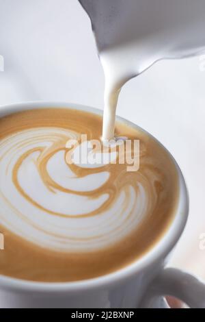 Der Barista gießt Latte-Schaum über Kaffee, Espresso und kreiert einen perfekten Cappuccino Stockfoto