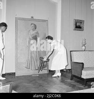 Die Hängung eines Staatsporträts von Königin Juliana in der königlichen Residenz in Fort Amsterdam in Willemstad unter dem wachsamen Auge der Gattin des Gouverneurs, Frau Struycken-Feldbrugge, ca. Oktober 1955 Stockfoto