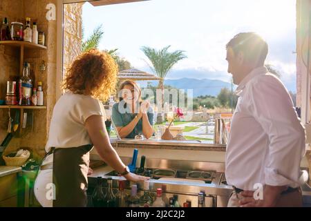 Mann und Frau, die in der Bar arbeiten und mit dem Kunden sprechen Stockfoto