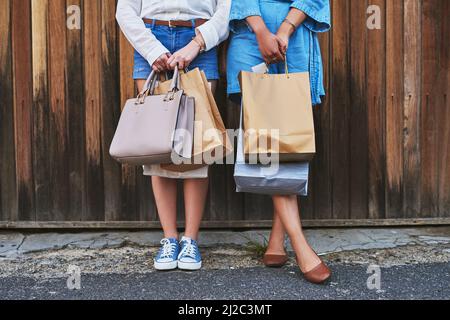 Wir dachten nur, dass wir es verdient hätten, diese Taschen heute zu halten. Ausgeschnittene Aufnahme von zwei unkenntlich gestandenen Freundinnen, die zusammen stehen und Einkaufstaschen halten Stockfoto