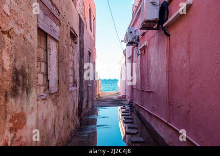 Blick auf das Karibische Meer durch verwitterte rot gestrichene Häuser in Willemstad, Curacao Stockfoto