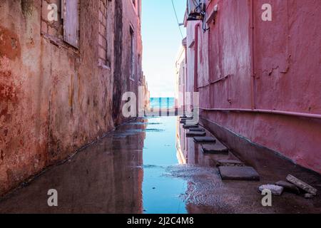 Blick auf das Karibische Meer durch verwitterte rot gestrichene Häuser in Willemstad, Curacao Stockfoto