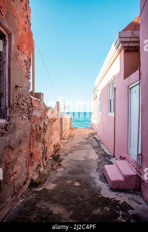 Blick auf das Karibische Meer durch verwitterte rot gestrichene Häuser in Willemstad, Curacao Stockfoto