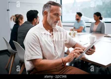 Darauf achten, dass er nichts vermisst. Ausgeschnittene Aufnahme eines hübschen, reifen Geschäftsmannes, der mit seinen Kollegen im Sitzungssaal an einem Meeting teilnahm Stockfoto