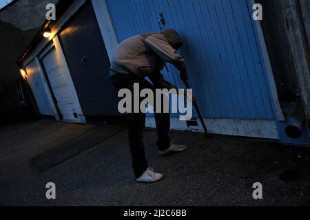 Ein Einbrecher versucht, eine Tür aufzubrechen. Stockfoto