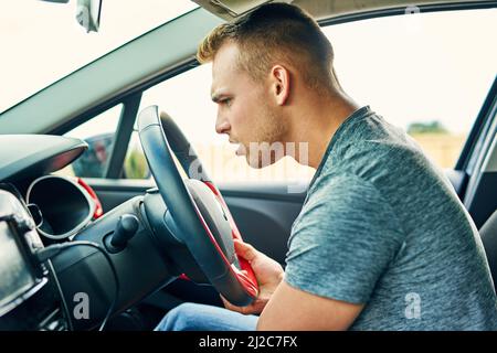 Was macht diesen lustigen Sound. Aufnahme eines jungen Mannes, der während der Fahrt Probleme mit seinem Auto hatte. Stockfoto